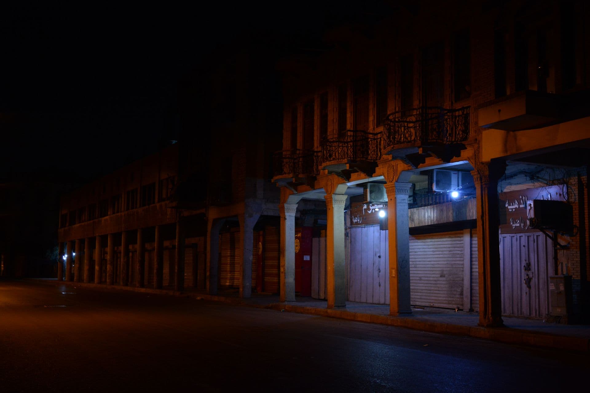 Rue commerçante aux rideaux baissés, de nuit